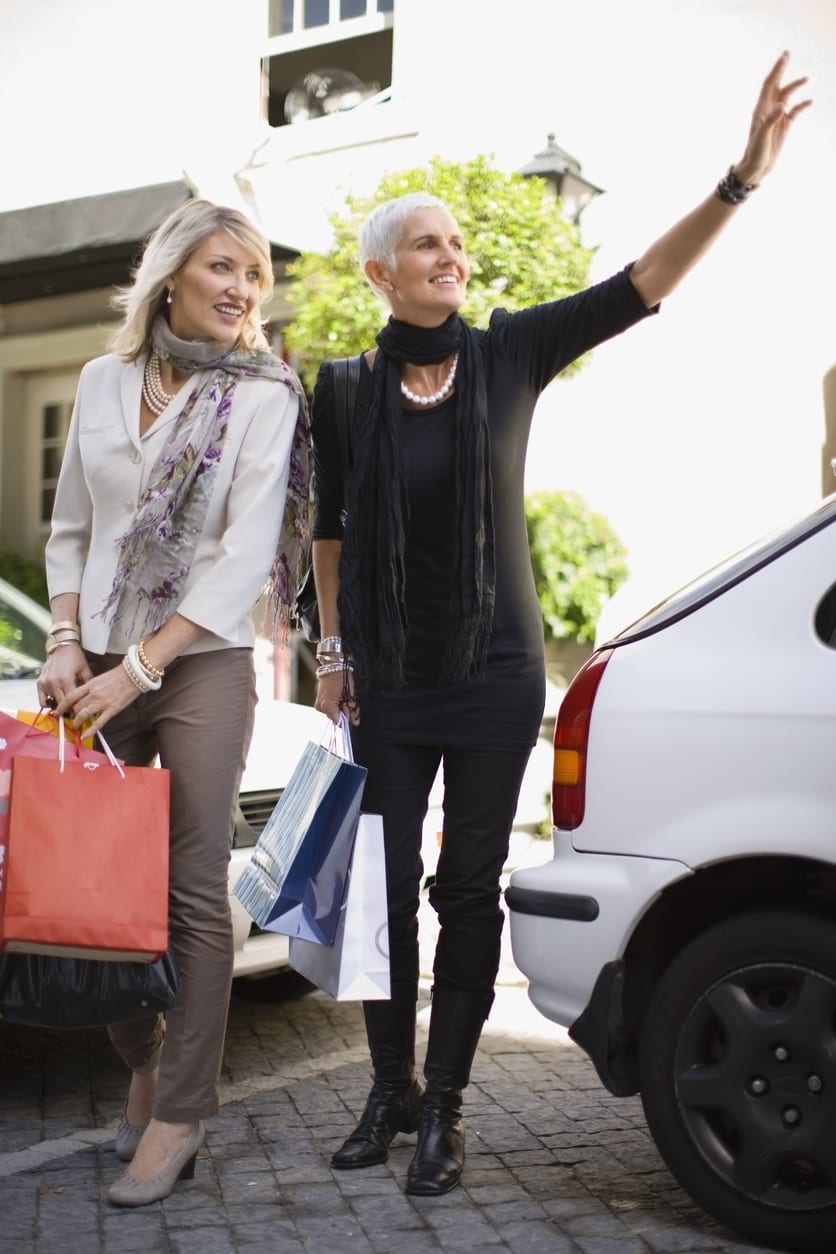 Older women carrying shopping bags dressed fashionably and smiling